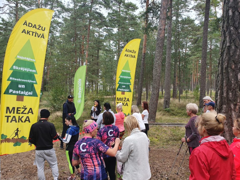 Meža takas atklāšanas pasākums. Daudz cilvēki - nūjotāji mežā pirms takas atklāšanas.